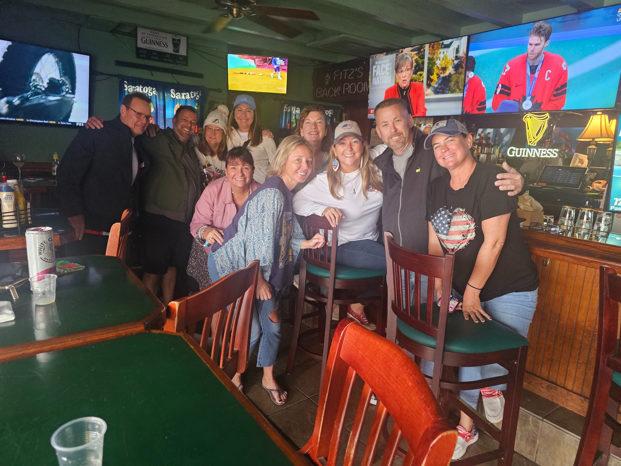 Group of friends enjoying drinks at Fitzgerald's bar with Guinness signs